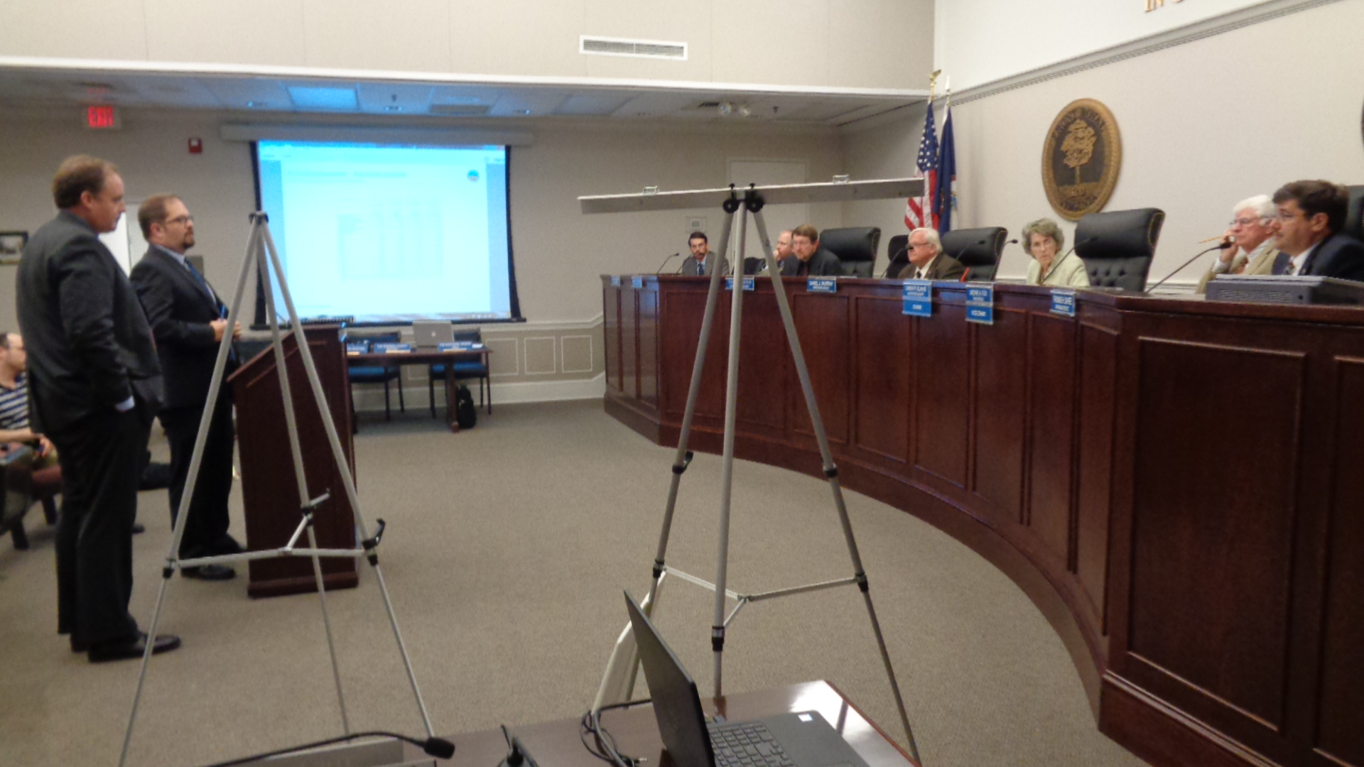 On Oct. 18, Ted Cole and Jesse Bausch, at podium, explain that the numbers weren’t crunching as well as they had been two weeks earlier. They continued to “un-crunch”, leading the County to opt out of a VRA Municipal Bond re-issue this month.